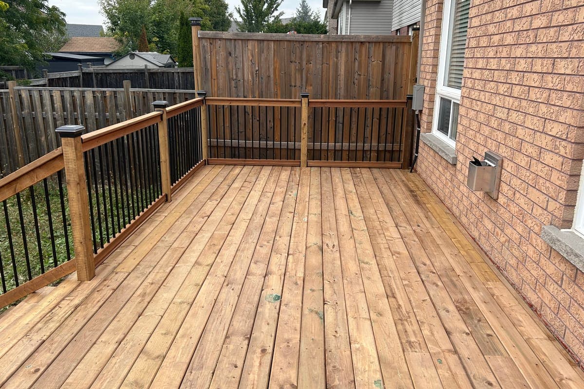 The same corner after: new wood decking and wooden railings with black pickets