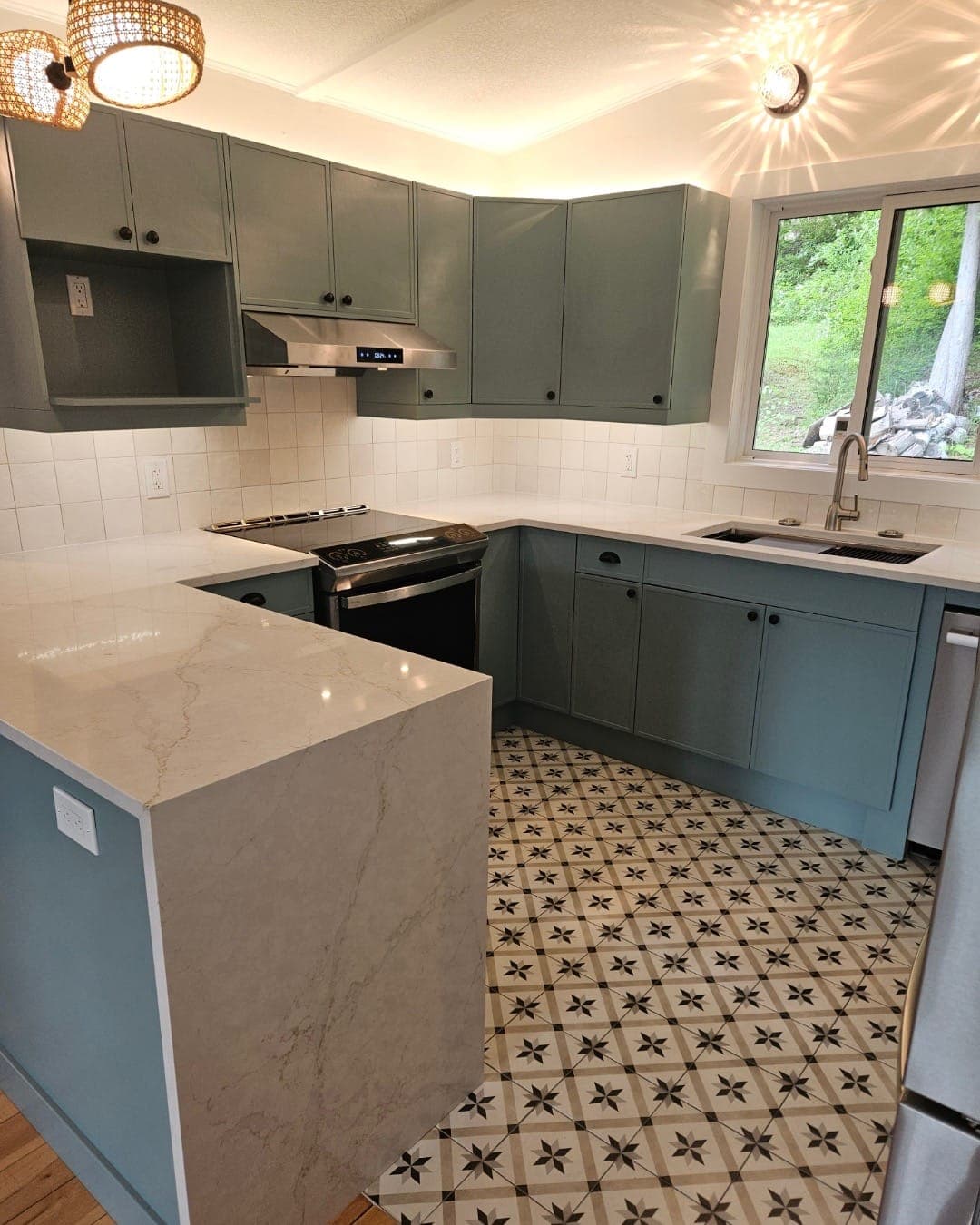 The finished kitchen from the dining side: the range wall, the waterfall counter end and the tiled floor