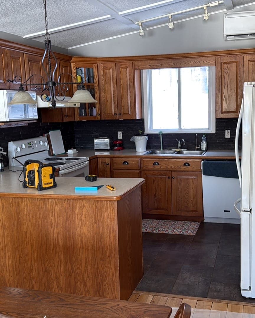 The kitchen before: oak cabinets, laminate counters and a dark brick-look backsplash