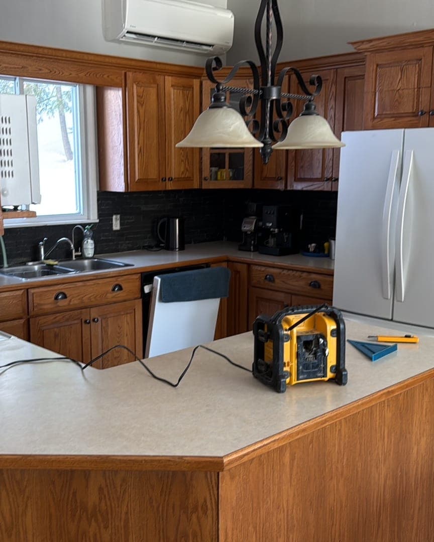 The kitchen before, from the dining side: oak uppers, laminate peninsula and the old sink run