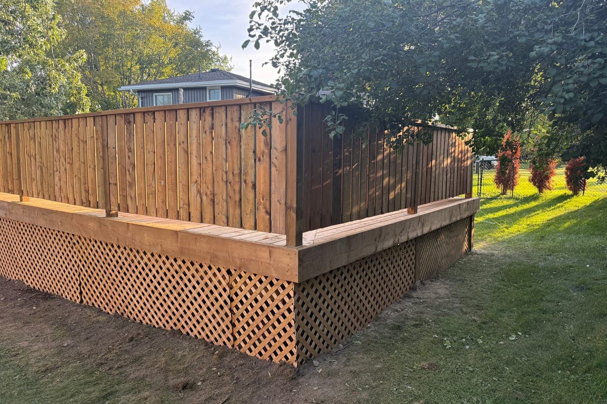 The pool deck from the lawn: deck-board railings above, lattice panels closing in underneath